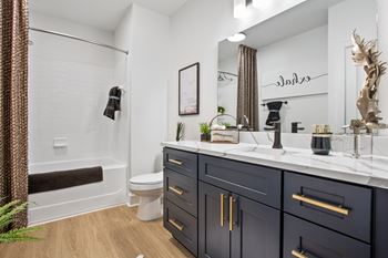 A bathroom with a white toilet, a white sink, and a black cabinet.